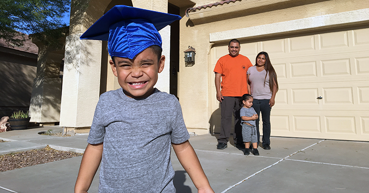 boy in graduation cap with family behind him