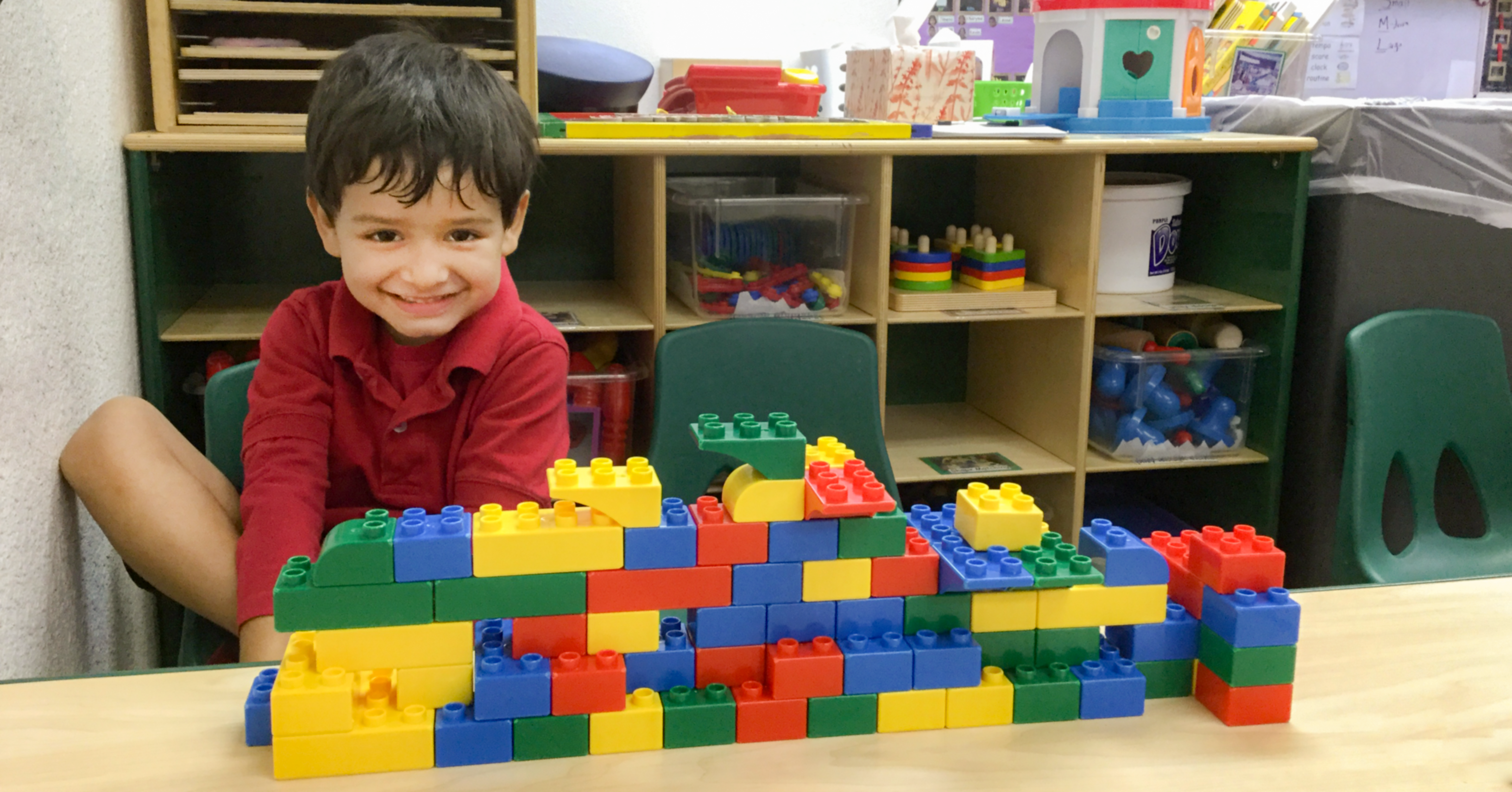 boy sitting at a table with lego structure