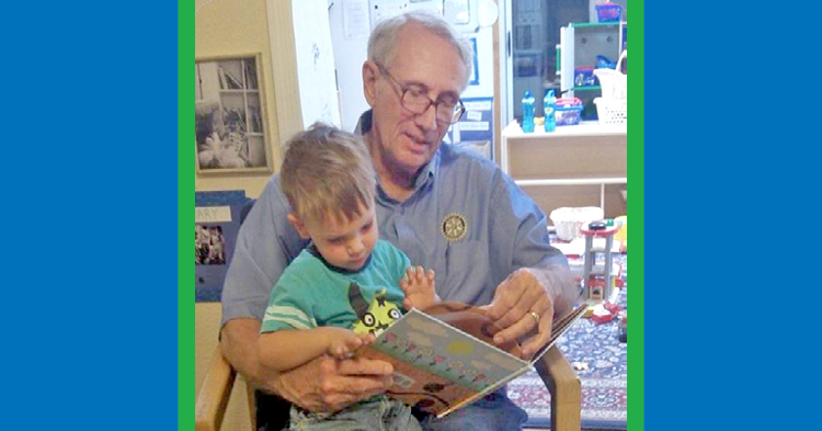 Elderly man reading with young boy