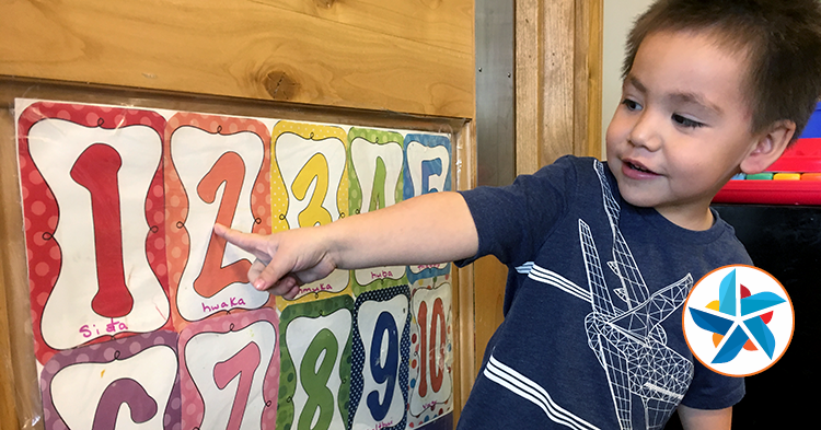 boy pointing to numbers on sign.