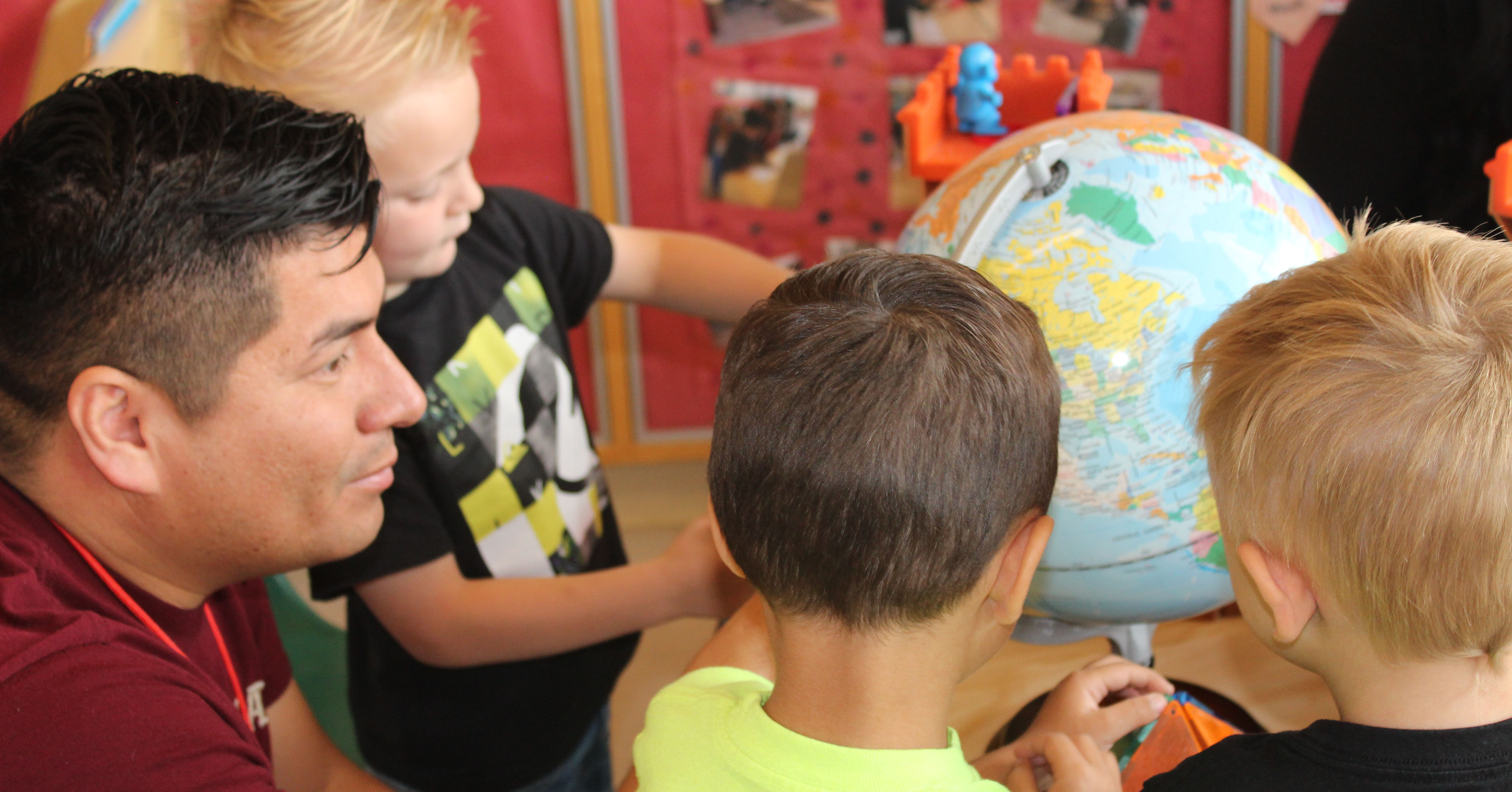 Male teacher and students looking at a globe.