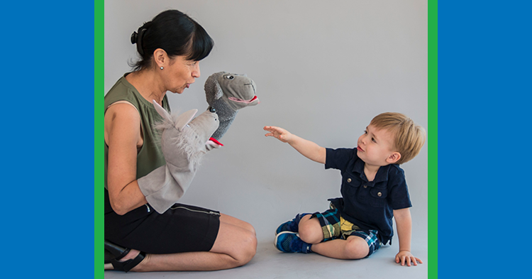 woman with puppet playing with toddler boy