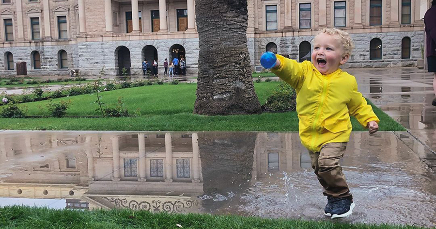 toddler in yellow rain jacket running