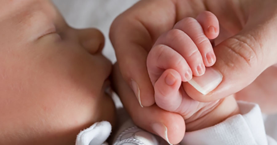 close up of newborn baby holding an adult hand