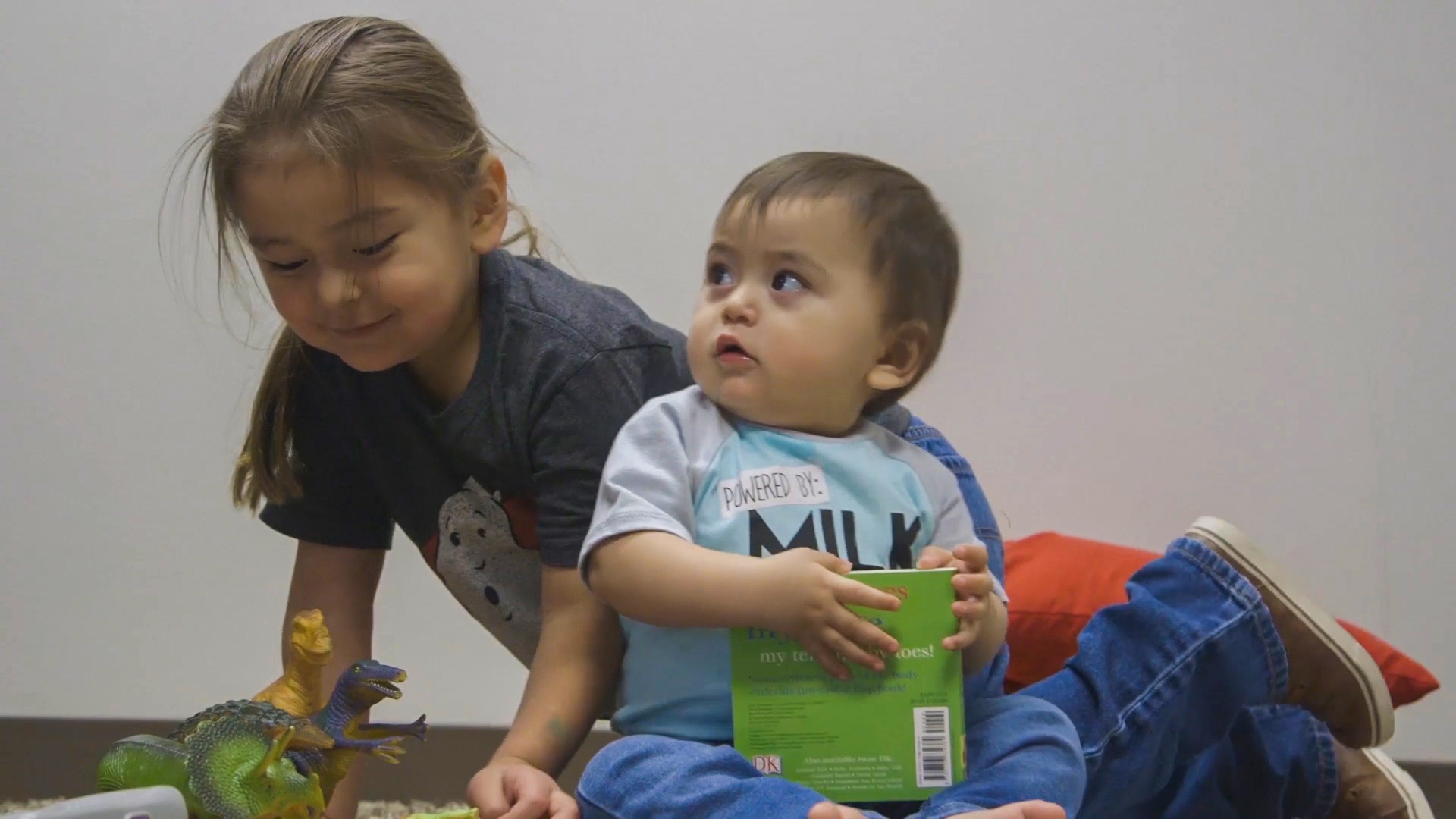 Two brothers, baby and toddler, playing on the floor.