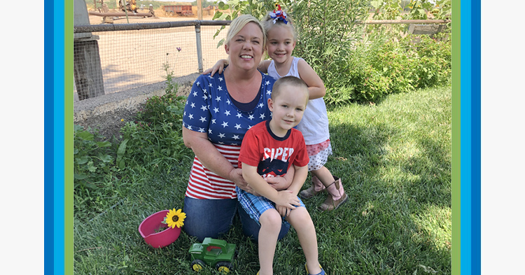 Mom kneeling, wearing a stars and stripes t-shirt, holding her son with a red tshirt and daughter standing next to her.