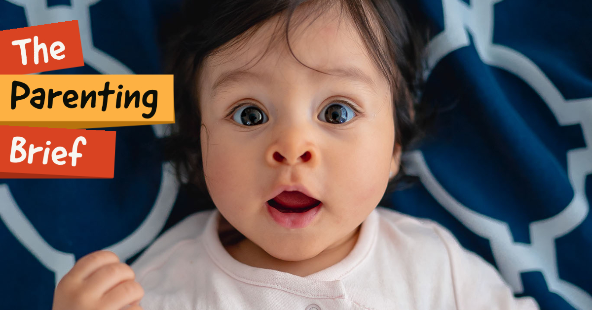 toddler looking surprised while laying on a blue blanket