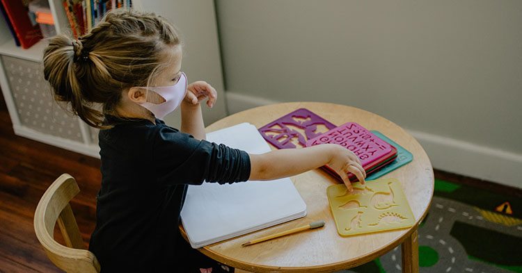 preschooler drawing at a table with stencils