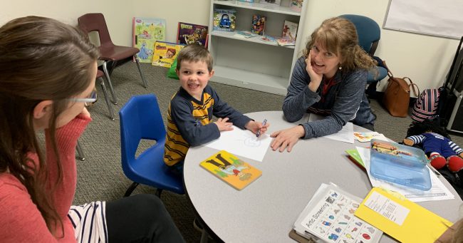 little boy at a table with woman doing a developmental screening.