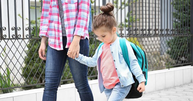 woman holding hand of young girl with backpack