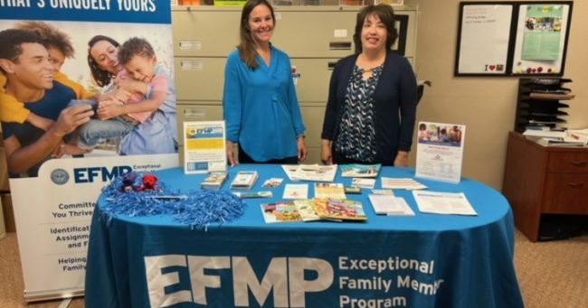 two woman standing behind a table with early childhood educational items and brochures