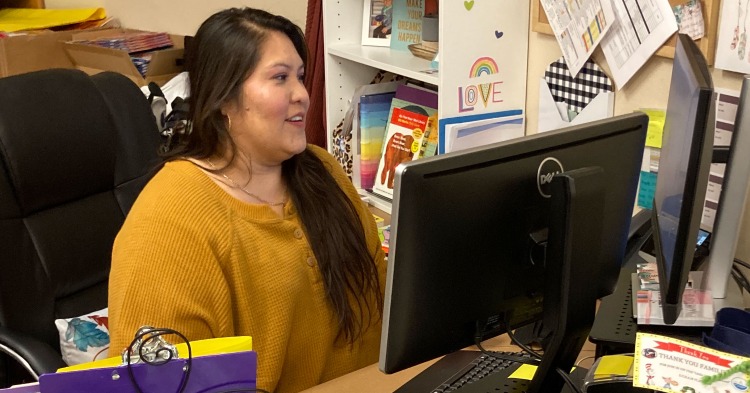 woman in yellow blouse sitting at computer desk