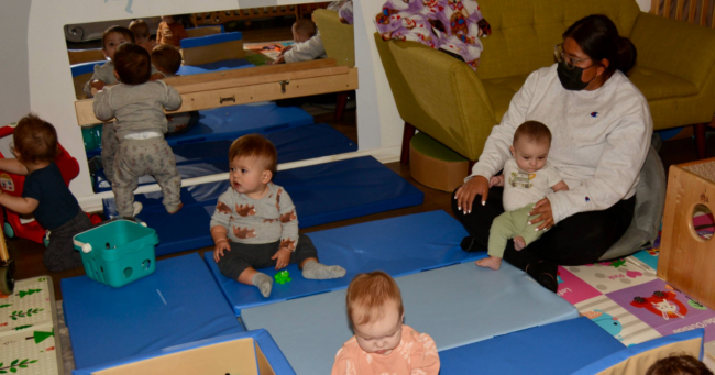 Teacher at Little Giants Spanish Immersion preschool in Phoenix engaging with infants and toddlers on mat. Lose access to Quality First